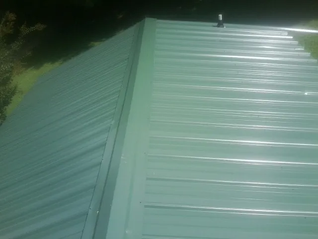 New green metal panels meeting at the ridge of a roof — Flat Roof Repair work by our crew in Imperial