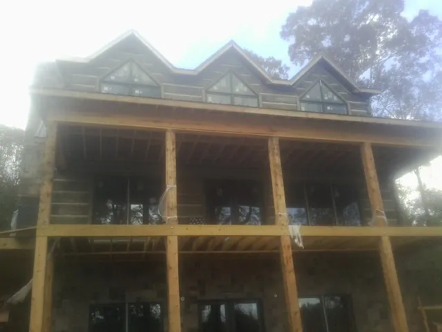 Dormers and porch framing on a large log home under construction — Roof Coating work by our crew in Imperial